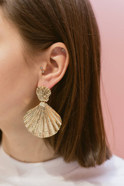 Ohrringe hängen an den Ohren. stylische Ohrringe mit Muscheln - Foto, Bild