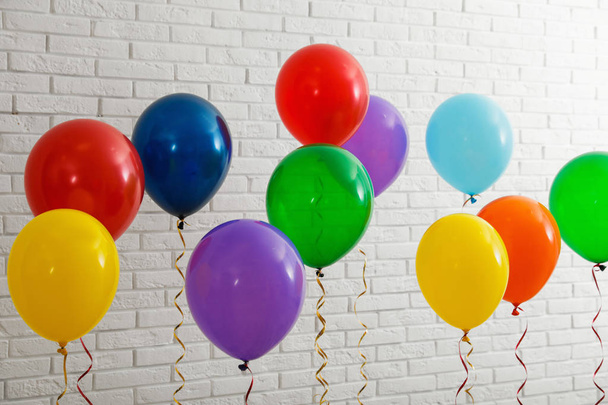 Bright balloons near brick wall. Celebration time - Фото, изображение