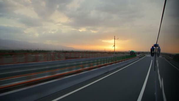 Autobus biegnie autostradą o zachodzie słońca, Chiny. - Materiał filmowy, wideo