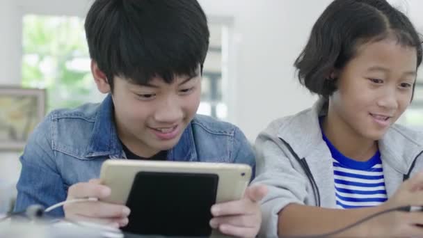 Zbliżenie azjatyckich cute girl i młodego chłopca grając w konkurencyjnej grze wideo na smartfony i tablety, trzymając je w poziomym trybie krajobrazu. 60fps w Dolly shot. - Materiał filmowy, wideo