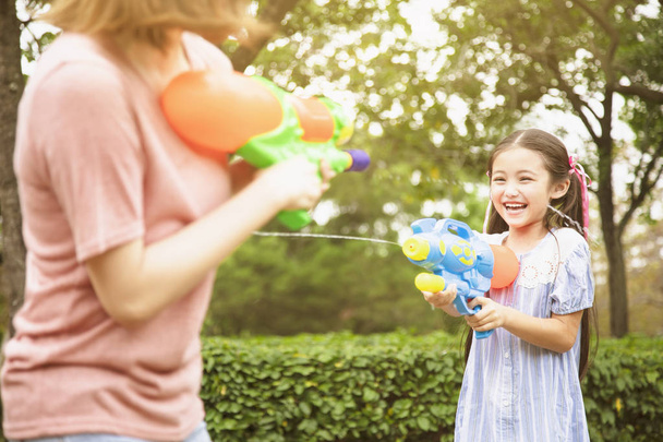 mother and little girls playing water guns in the park - Photo, Image