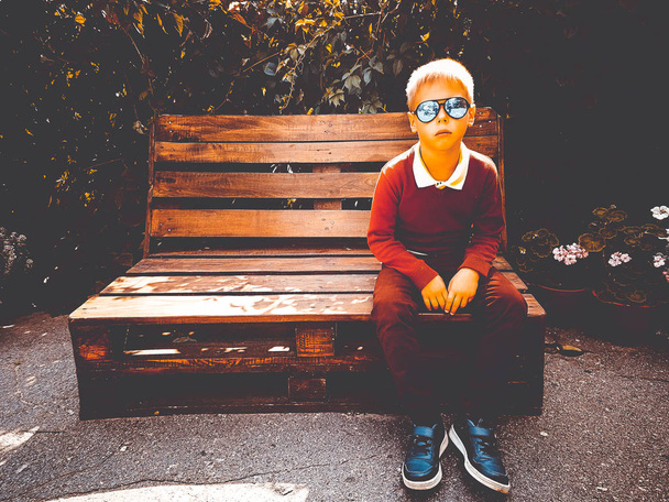 stylish boy sits on a wooden bench - Фото, зображення