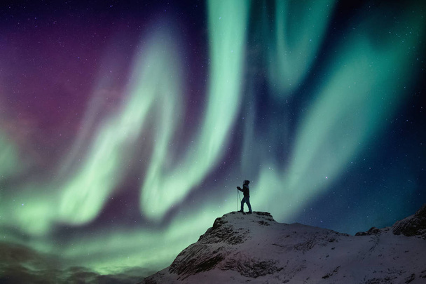 Férfi mászó állva havas csúcs a Aurora Borealis és a Star - Fotó, kép