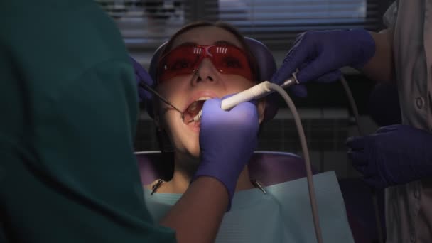 Hammaslääkäri hoitaa potilaita hampaan sähköhammasharjalla. Naisten muotokuva hammaspyörätuolissa
. - Materiaali, video