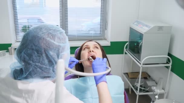 Nuori nainen hammaslääkärin hammastuolin ennaltaehkäisevässä tarkastuksessa. Hampaiden hoito käsite
. - Materiaali, video