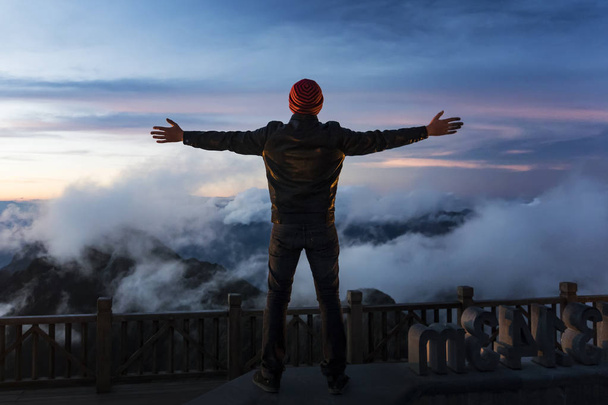 Zonsondergang op Fansipan, silhouet van de mens staat op de top van de berg en het verspreiden van de hand voor zonsopgang. Emotionele scène. Freedom Travel avontuur en Business Victory concept. - Foto, afbeelding