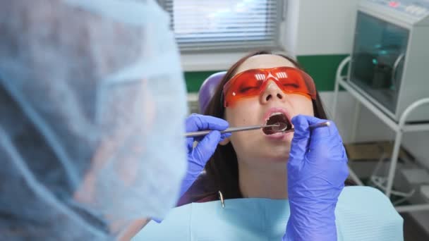 Menina em óculos de proteção no exame preventivo em cadeira dentária na clínica odontológica. Dentes conceito de cuidado
. - Filmagem, Vídeo