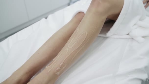 Lähikuva naisen jalat peitetty geelillä valkoisella pöydällä, potilas odottaa laser karvojen poisto menettely, hidastettuna
. - Materiaali, video