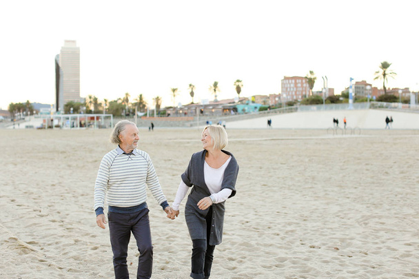 砂浜を走り、手をつないで走る先輩夫と笑顔の妻. - 写真・画像