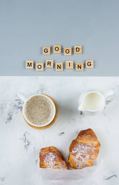 Dobré ráno snídaně minimální koncepce. Šálek kávy, croissant a text dobré ráno na růžovém šedém pozadí. Plochá ležela - Fotografie, Obrázek
