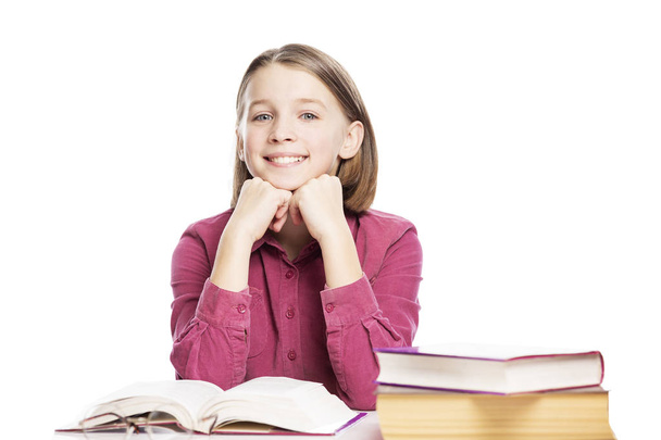Smiling teen girl sitting at a table with books. Isolated on a white background. - Foto, imagen