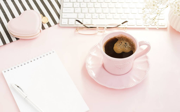 espacio de trabajo femenino con teclado y taza de café sobre fondo rosa
  - Foto, imagen