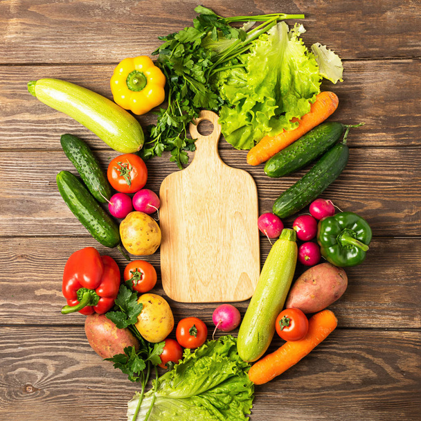 Fresh green vegetables zucchini cucumber greens pepper cutting board on wooden background. Healthy food vegetarianism. - Фото, изображение