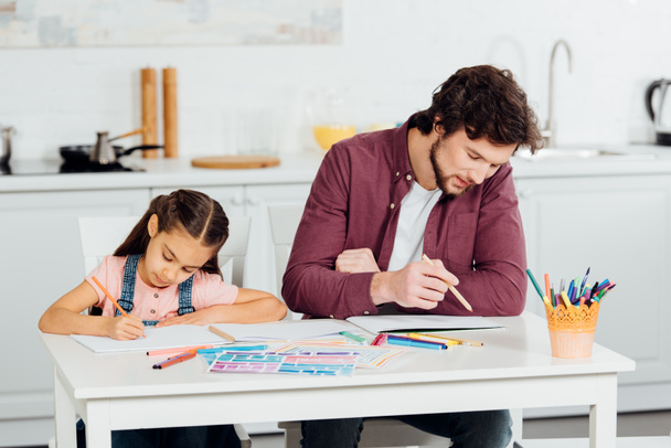 knappe vader en schattige dochter tekening op papers thuis  - Foto, afbeelding