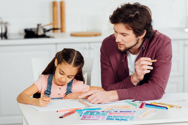 handsome father pointing with finger at paper near cute daughter  - Photo, Image