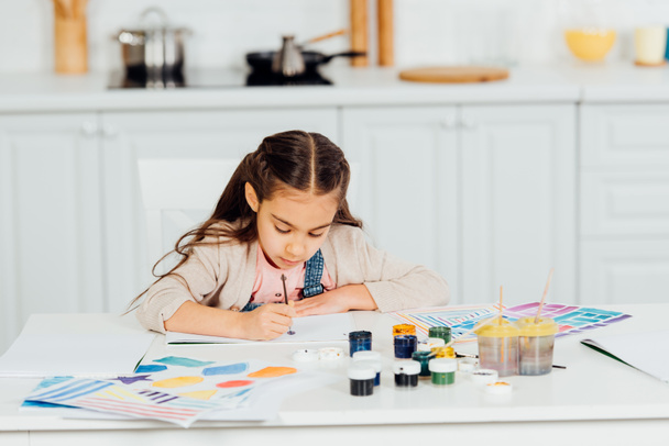 concentrado e bonito criança pintura em papel em casa
  - Foto, Imagem