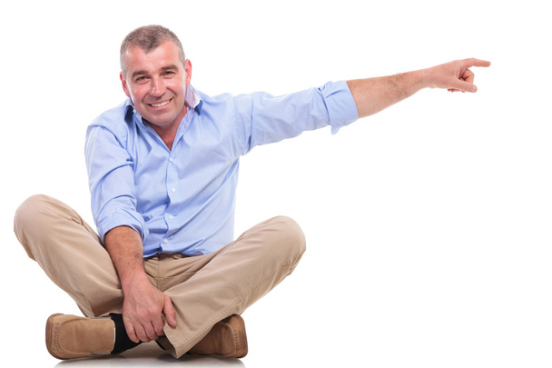 casual middle aged man sits and points - Photo, Image