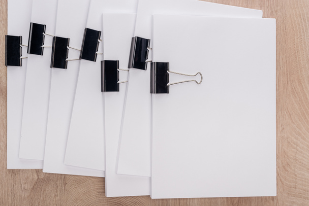 top view of stacks of blank paper with metal binder clips and copy space on wooden table - Photo, Image