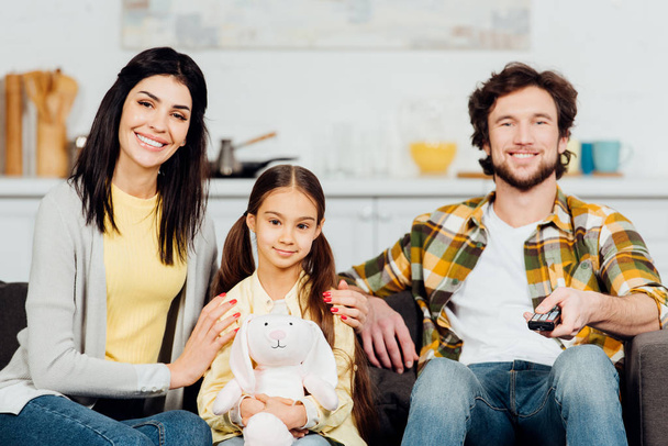 happy man holding remote controller near wife and daughter  - Photo, Image