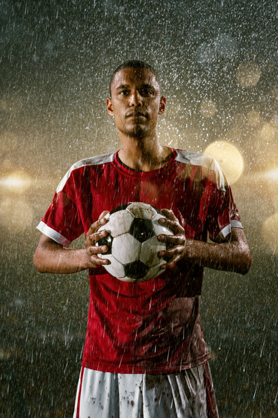Giocatore di calcio sullo stadio antipioggia notturno professionale di calcio. Giocatore sporco in gocce di pioggia con palla da calcio
 - Foto, immagini