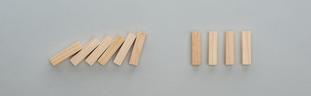 panoramische foto van vallende houten blokken geïsoleerd op grijs, domino effect concept - Foto, afbeelding