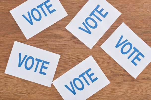 Ansicht weißer Karten mit Wahlschriftzug auf Holztisch verstreut - Foto, Bild