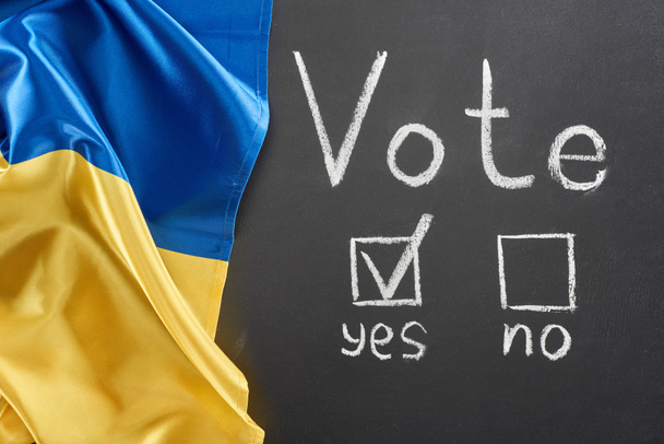 felülnézet a szavazás betűkkel, és pipa közelében igen szó fekete Chalkboard közelében ukrán zászló - Fotó, kép