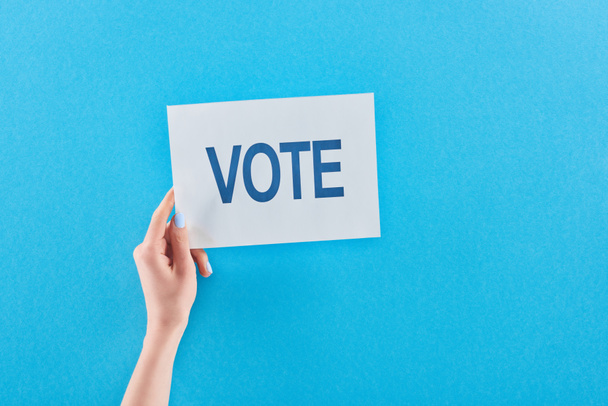 partial view of woman holding white card with vote lettering on blue background  - Foto, Bild