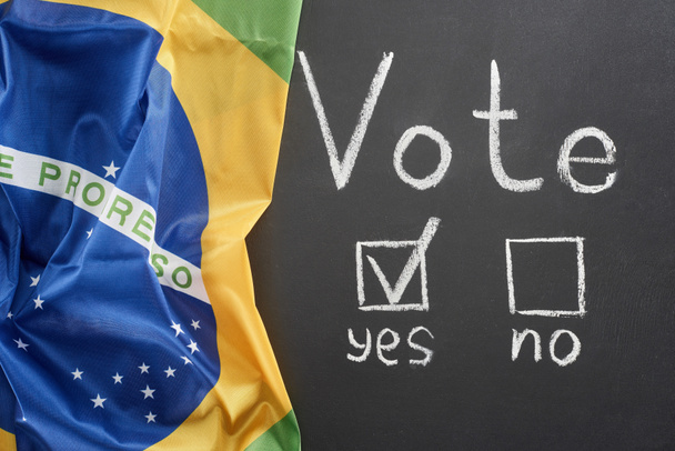 vista superior da palavra de voto branco e marca de verificação perto sim palavra no quadro preto perto da bandeira do Brasil
 - Foto, Imagem