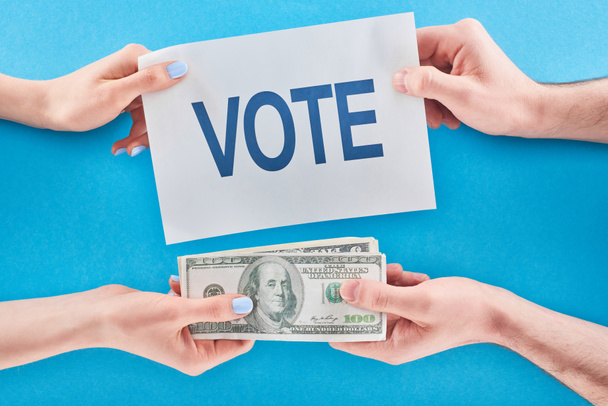 cropped view of man giving bribe for vote to woman on blue background - Photo, Image