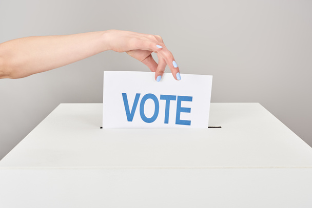 vista parziale di donna che mette carta con voto in scatola isolata su grigio
 - Foto, immagini