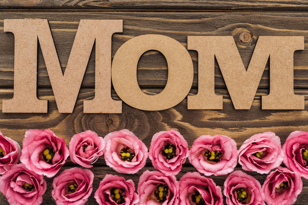 top view of pink eustoma flowers and mom word on wooden table - Zdjęcie, obraz