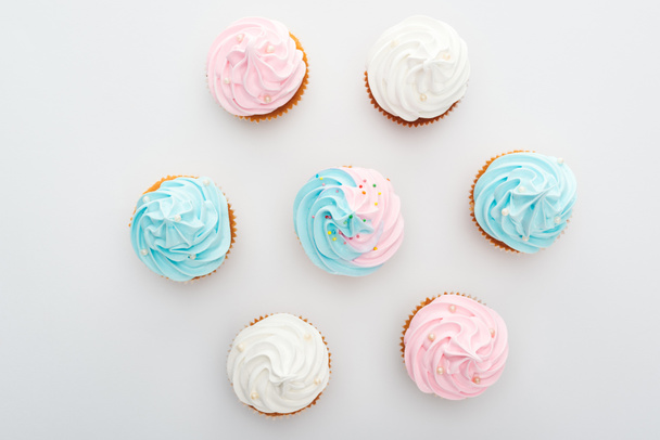 top view of delicious white, pink and blue cupcakes with sprinkles Isolated On White - Фото, зображення