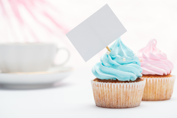 selective focus of tasty cupcakes decorated with sprinkles and blank card - Foto, Imagem