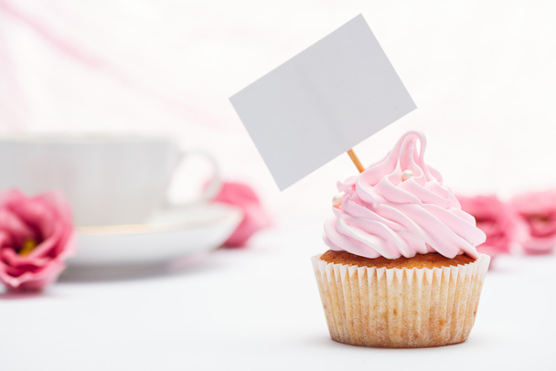 selective focus of delicious pink cupcake decorated with sprinkles and blank card - Φωτογραφία, εικόνα