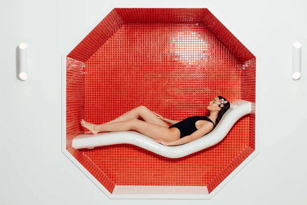 vista lateral da jovem atraente em maiô deitado no centro de spa
 - Foto, Imagem