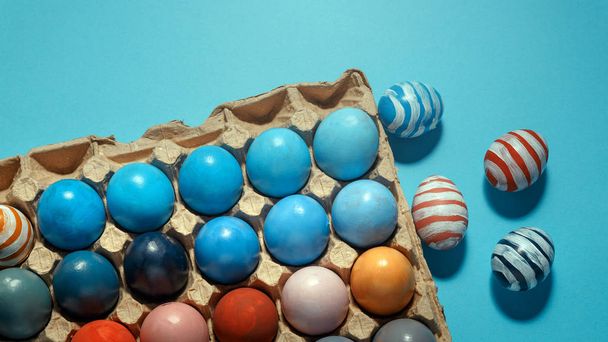 Colorful Easter eggs lie in a row on a blue background, top view - Foto, afbeelding