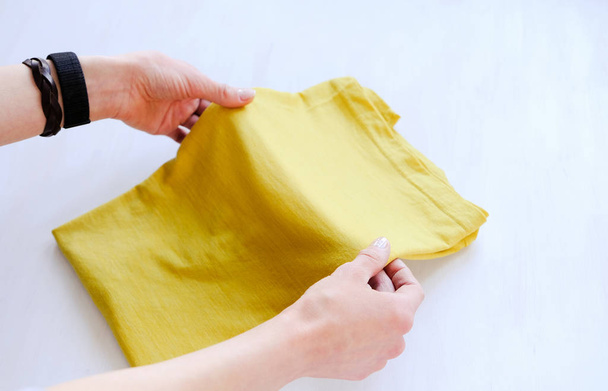 Woman tidy folds male t-shirt on a white background - Photo, image