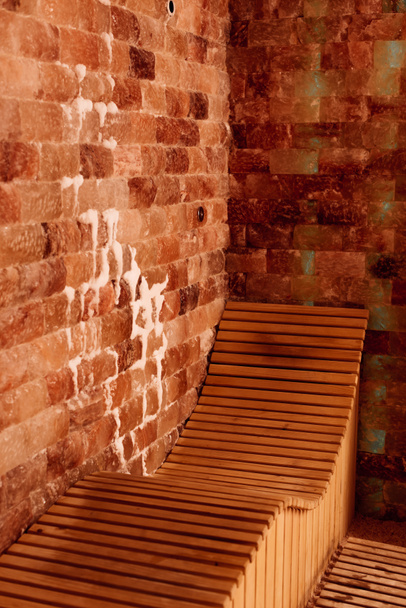 Ξύλινος πάγκος σε κέντρο σπα με ανάγλυφους τοίχους - Φωτογραφία, εικόνα