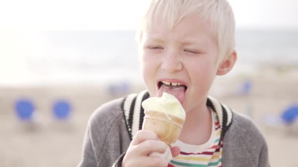 Chłopak blond zjada lody. - Materiał filmowy, wideo