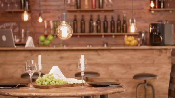 Een houten ronde tafel in een leeg restaurant met kaas en druiven voorgerecht - Video