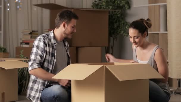 Joyeux couple déménageant à la maison dans la nuit déballage effets assis sur le sol
 - Séquence, vidéo