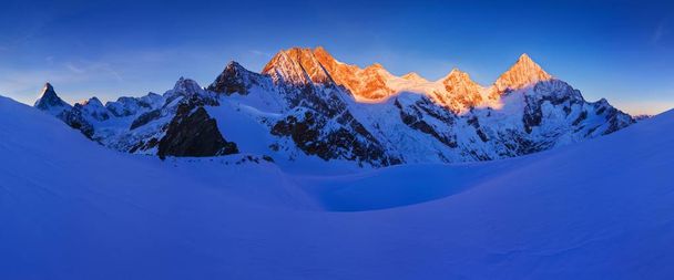 青空の下で雪の中の山々の風光明媚な眺め - 写真・画像