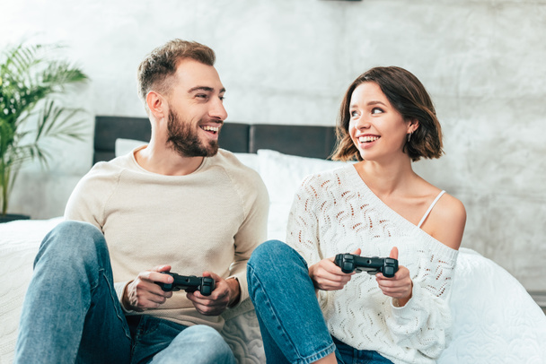 happy man looking at cheerful woman holding joystick at home  - Photo, Image