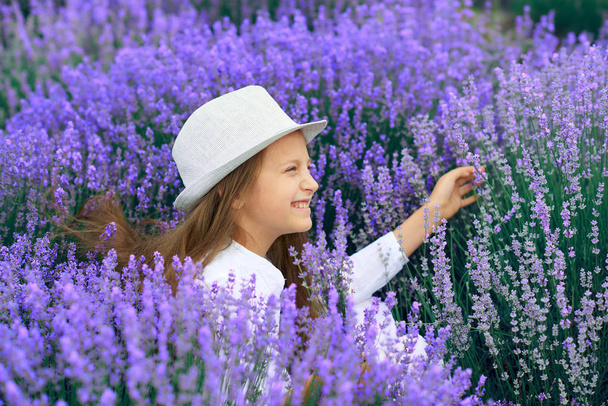 girl child is in the lavender flower field, beautiful summer landscape - Foto, imagen