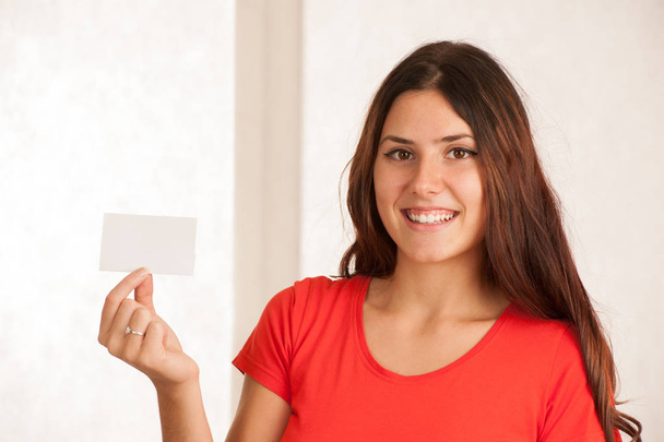 Beautiful young woman in red t shirt holds blank card over white - Foto, Bild