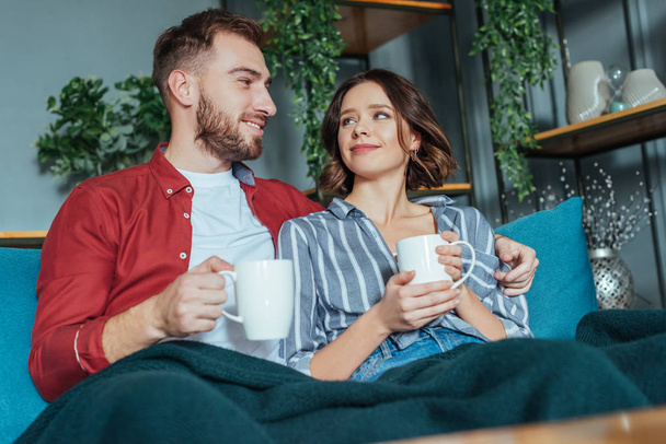 low angle view of happy man looking at attractive woman with cup  - Photo, Image