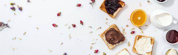 tiro panorâmico de torradas com engarrafamento, creme de chocolate e creme de queijo perto de flores secas em branco
  - Foto, Imagem