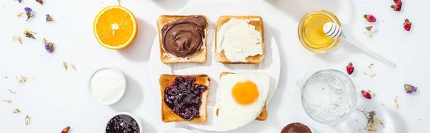 Panoramaaufnahme von leckeren Toasts mit Marmelade, Frischkäse, Schokoladencreme und Freund-Ei auf Weiß  - Foto, Bild