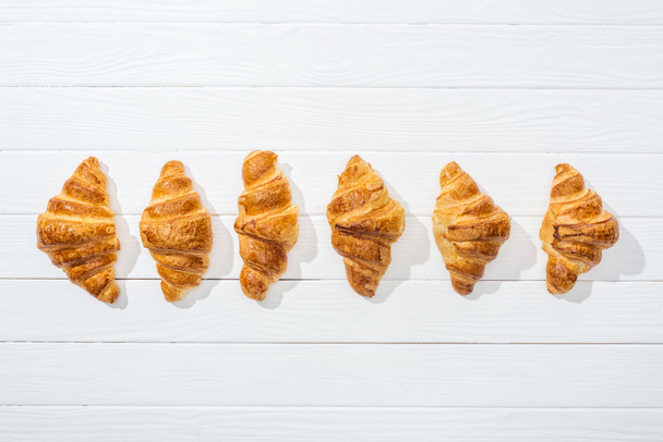 flat lay of sweet, tasty and fresh croissants on white surface  - Fotografie, Obrázek